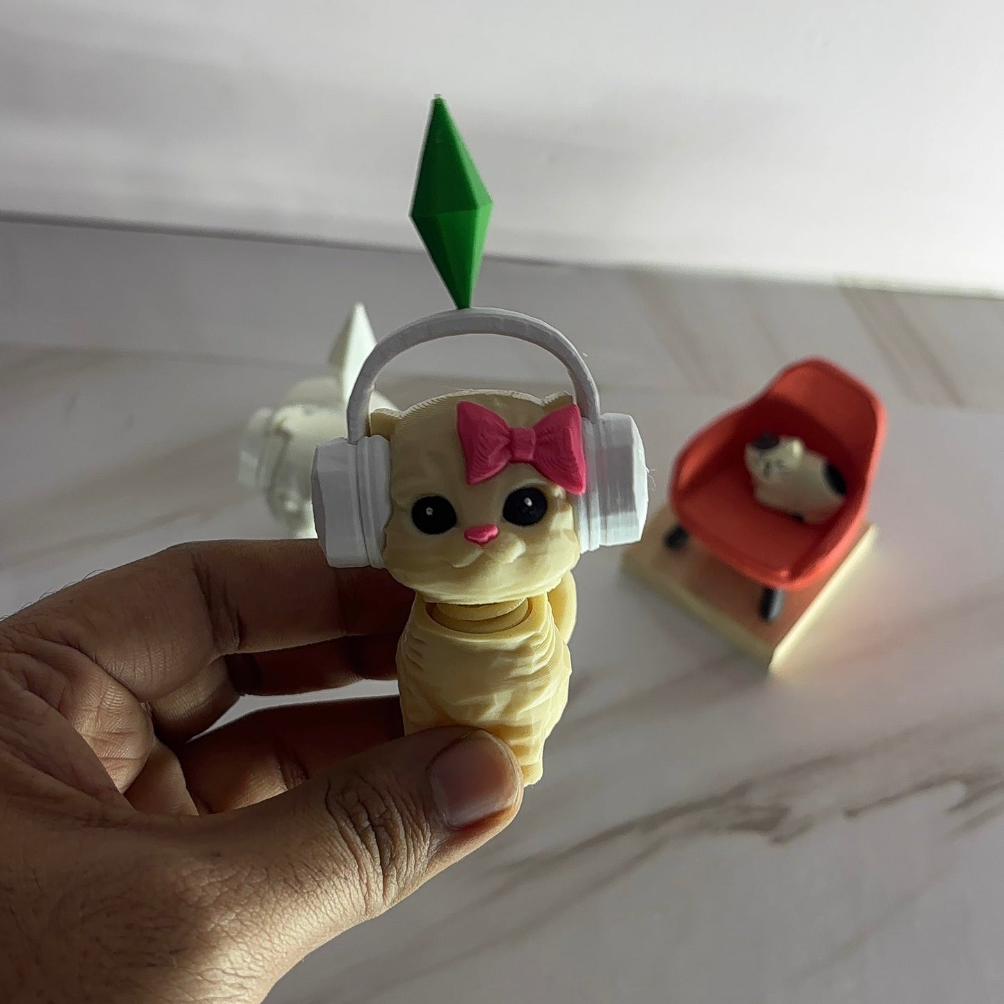 Small plush toy with a green top held by a hand on a light-colored surface.