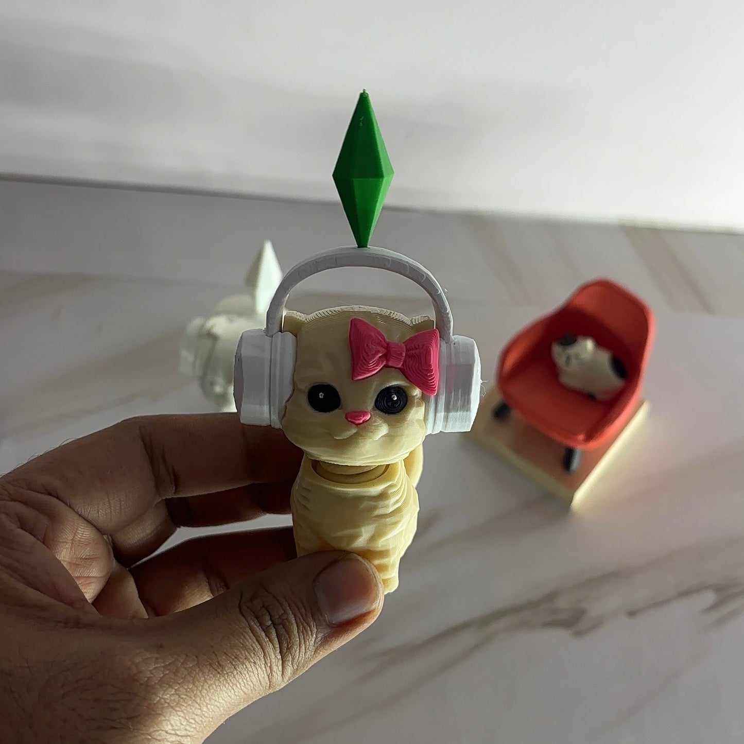 Small figurine with headphones and a bow held by a hand on a white surface