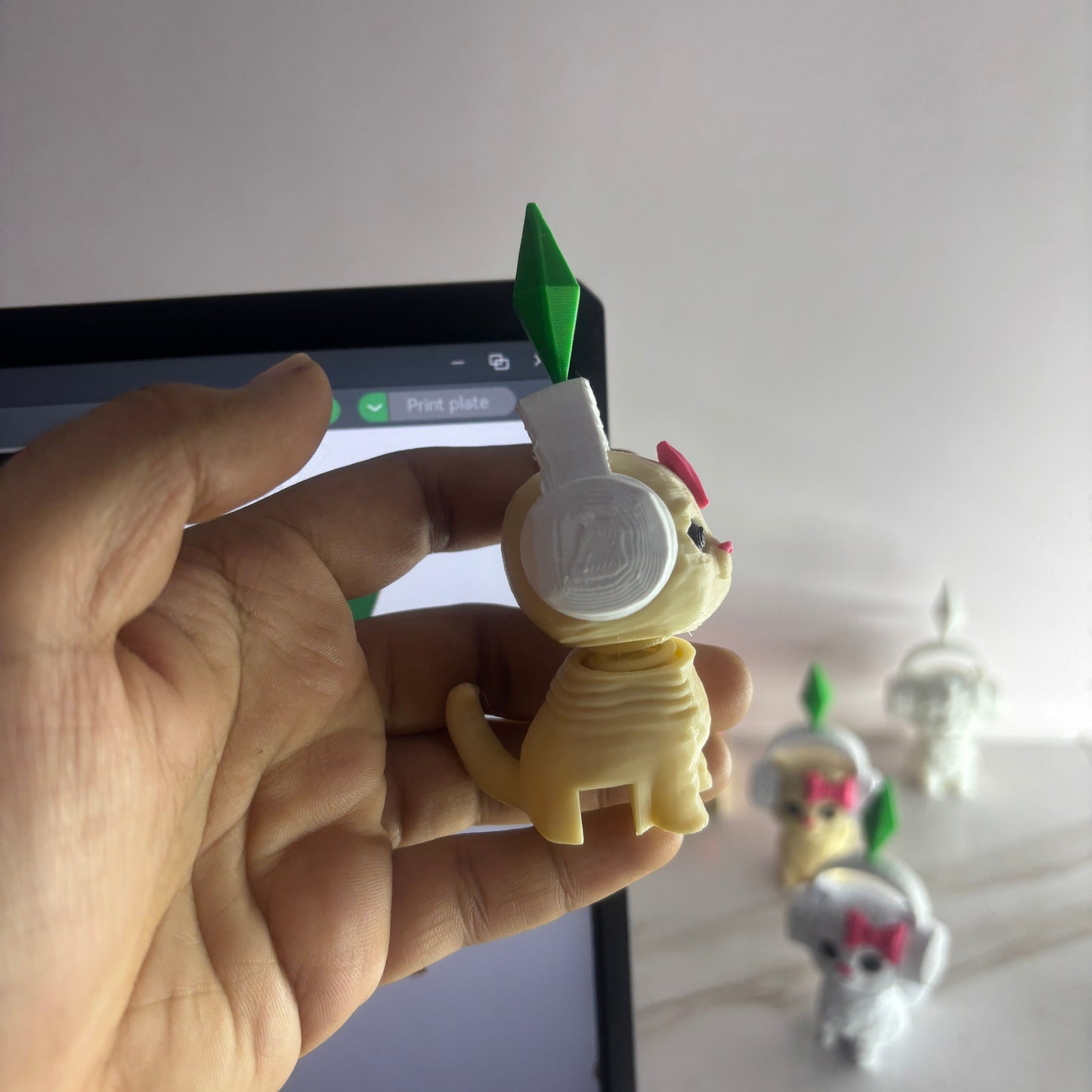 Hand holding a small figurine with a green spike and white base against a blurred background