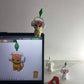 Toy figure interacting with a digital device displaying a character on a white wall background