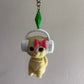 Keychain with a cat wearing headphones and a pink bow, hanging from a hook.