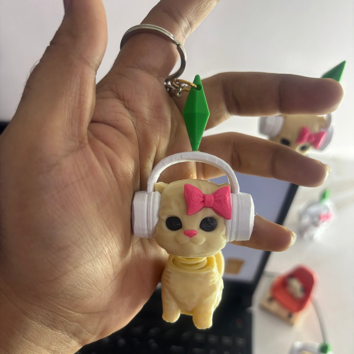 Hand holding a small figurine with a white base, pink bow, and black eyes.