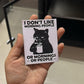 Hand holding a small card with a black cat illustration and text.